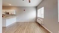 Located at 3276 Jim St in Rapid City, South Dakota, this efficiently designed single-floor unit offers a thoughtful layout across a compact footprint. The space is finished with light wood-look luxury vinyl plank flooring throughout, complemented by soft gray walls and bright white trim that create a clean, contemporary aesthetic.

The kitchen is a standout feature, outfitted with crisp white shaker-style cabinetry extending to the ceiling for ample storage, light-toned countertops, and a suite of black appliances including a refrigerator, electric range with overhead microwave, dishwasher, and a stainless steel sink. The kitchen flows seamlessly into the open living area, which benefits from natural light through a large window and is equipped with a ceiling fan and a wall-mounted HVAC unit for year-round comfort.

The bathroom features a clean, all-white tub and shower combination with chrome fixtures, maintaining the unit's consistent modern and minimal style. A dedicated utility room houses the water heater and provides additional functional space.

Overall, the unit presents a well-organized, move-in-ready interior with a cohesive design palette, practical amenities, and an efficient use of space suited for comfortable everyday living.
