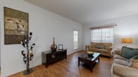 This single-floor residence offers a thoughtfully organized layout that balances comfort and functionality throughout. The living room is a welcoming focal point, characterized by vaulted ceilings that amplify the sense of openness, warm hardwood-style flooring, and multiple windows fitted with blinds that invite abundant natural light. The space comfortably accommodates a full seating arrangement, making it well-suited for both relaxing and entertaining.

Adjacent to the living area, the dining space features a round high-top table with seating for several guests and connects seamlessly to the kitchen. The kitchen is efficiently designed with white cabinetry accented by wood trim, a coil-top electric range, a dishwasher, and granite-look countertops, providing ample workspace for meal preparation.

The bedroom is a tranquil retreat with vaulted ceilings, hardwood-style flooring, a large window with sheer curtains, and direct access to an adjoining room, likely a walk-in closet or bathroom. The full bathroom includes a tub-shower combination, a vanity with countertop space, and hardwood-style flooring.

Completing the home is a dedicated in-unit laundry area with a full-sized washer and dryer, accompanied by overhead wire shelving for added storage convenience.