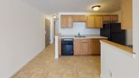 Located at 1 Lilac in Dover, New Hampshire, this single-floor unit offers a clean, functional layout designed for comfortable everyday living. The open-concept living and dining area is finished with neutral wall-to-wall carpeting, flush-mount ceiling lighting, and baseboard heating running along the perimeter — a practical feature well-suited to New England's climate. The space flows naturally into the kitchen, which is appointed with warm oak cabinetry, light countertops, tile flooring, a double sink, a dishwasher, and a peninsula that provides a natural boundary between the kitchen and living areas. The bedroom is a well-proportioned, carpeted room featuring a six-panel door, baseboard heat, and a window that allows natural light to filter in. The full bathroom is outfitted with a tub-shower combination, tile flooring, and a vanity with a striking granite countertop, adding a refined touch to the otherwise understated interior. Throughout the unit, the white walls and neutral finishes create a bright, clean aesthetic that offers a versatile backdrop. The overall layout is practical and well-organized, making efficient use of the available space across a single level.