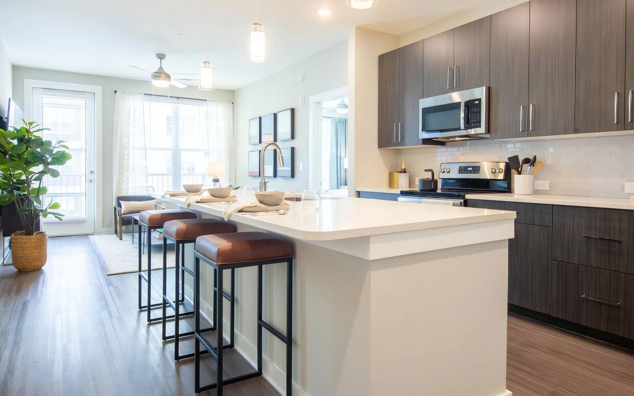 Open Kitchen Featuring Bar Seating and Adjacent Living Area - The Elden Galleria