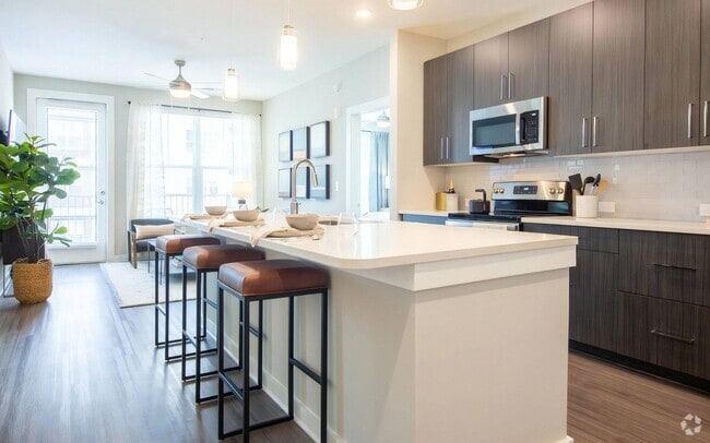 Open Kitchen Featuring Bar Seating and Adjacent Living Area - The Elden Galleria