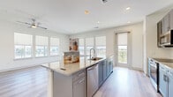 Located in Frisco, TX, this well-appointed single-story home offers three bedrooms and two bathrooms across a thoughtfully designed open floor plan. Light wood-style flooring flows throughout the main living areas, while neutral tones and recessed lighting create a clean, modern aesthetic.

The open-concept kitchen and living room serve as the heart of the home, anchored by a large center island with granite countertops and an undermount sink. Gray shaker-style cabinetry, a decorative tile backsplash, and stainless steel appliances — including a refrigerator, range, microwave, and dishwasher — complete the kitchen. The living area features a ceiling fan and a bank of windows offering views of the surrounding neighborhood.

The primary bedroom is generously sized, carpeted for comfort, and filled with natural light from multiple windows. It is accompanied by a walk-in closet with built-in shelving and hanging rods. The bathrooms include granite-topped vanities with gray cabinetry, tile flooring, and a tub-shower combination. The additional bedrooms are also carpeted and well-lit with outdoor views.

Practical spaces include a dedicated laundry room with side-by-side washer and dryer hookups and built-in shelving, a pantry, and a utility room. Four closets provide generous storage throughout the home.