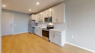 Located at 500 W Lake St in Minneapolis, MN, this one-bedroom, one-bathroom unit offers a well-designed layout across a single floor. The open-concept kitchen and living area serves as the heart of the space, featuring light hardwood-style flooring, soft blue-gray walls, and recessed lighting. The kitchen is outfitted with crisp white shaker-style cabinetry, white subway tile backsplash, quartz countertops, and a full suite of stainless steel appliances including a refrigerator, electric range, microwave, and dishwasher — combining functionality with a clean, modern aesthetic. The living area benefits from a large window that brings in natural light and frames views of the surrounding Minneapolis cityscape. The bedroom is carpeted for comfort, finished in neutral gray tones, and includes a window with outdoor views. It is complemented by a spacious walk-in closet equipped with wire shelving and ample storage on multiple levels. The full bathroom features large-format tile flooring, a white shaker vanity with quartz countertop, an illuminated LED mirror, and a shower-tub combination. In-unit laundry adds everyday convenience, rounding out this efficiently designed urban residence.