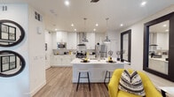 This thoughtfully designed single-floor residence offers a seamless blend of modern aesthetics and functional living. The open-concept kitchen is a standout feature, showcasing crisp white shaker cabinetry, marble-look quartz countertops, a large center island with bar seating, and a suite of stainless steel appliances including a range with a sleek chimney hood, built-in microwave, and French door refrigerator. Polished pendant lights hang above the island, adding an industrial-chic touch. Wood-look flooring flows throughout the main living areas, anchoring the bright, neutral palette. The living room is generously sized and features recessed lighting, a modern ceiling fan, and sliding glass door access to an outdoor area, filling the space with natural light. The bedroom offers plush carpeting, a ceiling fan, window with blinds and draping curtains, and a calm, restful atmosphere. The bathroom is finished in large-format white tile with a clean vanity, framed mirror, and ample storage. A dedicated in-unit laundry room with side-by-side washer and dryer adds everyday convenience. Throughout, the space maintains a cohesive contemporary style with bold yellow accent décor, large wall mirrors, and curated artwork.