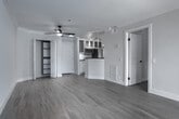 Located at 1959 Rochester Ave in the desirable Westwood neighborhood of Los Angeles, this single-floor residence has been thoughtfully updated with contemporary finishes throughout. Light wood-tone flooring runs continuously across the living spaces, complementing a neutral, warm color palette that lends the interior a clean and cohesive feel.

The open living area is a standout, featuring crown molding, a ceiling fan, and a fireplace flanked by a window. Floor-to-ceiling sliding glass doors provide direct access to an outdoor balcony, flooding the space with natural light and views of surrounding greenery. Built-in shelving adds functional character near the entryway.

The galley-style kitchen is efficiently designed with white cabinetry—including glass-front upper cabinets—dark countertops, a white tile backsplash, a deep undermount sink with a matte black faucet, and stainless steel appliances including a gas range, microwave, and refrigerator. Track lighting completes the kitchen's polished look.

The bedroom offers a calm, airy atmosphere with hardwood flooring and direct access to a well-appointed bathroom. The bathroom features a glass-enclosed walk-in shower finished in large-format grey stone-look tile, a built-in niche, a bench seat, and mosaic tile flooring—all accented with dark matte hardware.