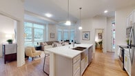 Located at 29 N Hancock St in the heart of Madison, Wisconsin, this thoughtfully designed single-floor residence offers a bright, contemporary living experience. The open-concept layout seamlessly connects the kitchen, dining, and living areas, creating a generous and cohesive space ideal for both everyday living and entertaining. The kitchen is a standout, featuring a large center island with a quartz waterfall countertop, undermount sink, stainless steel appliances, gray shaker-style cabinetry with gold hardware, and pendant lighting overhead. A bay-windowed dining nook provides an intimate setting with ample natural light and neighborhood views. The living room is anchored by large windows overlooking the street, filling the space with daylight and urban scenery. Light hardwood flooring flows consistently throughout the unit, complementing the clean, neutral color palette. The bedroom is generously proportioned with elevated ceilings and direct access to a well-appointed en-suite bathroom, complete with a tub-shower combination, hardwood flooring, and matching gray cabinetry. A dedicated office nook offers a quiet workspace with natural light. Additional highlights include a stacked in-unit washer and dryer and a bright hallway with tasteful decor accents.