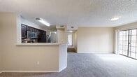 This two-bedroom, two-bathroom residence in Westminster, Colorado offers a well-organized single-floor layout that maximizes functionality. The open-concept living area serves as the heart of the home, featuring plush carpet underfoot, a textured ceiling, and a classic brick fireplace framed by a sliding glass door that invites natural light and outdoor views. The kitchen is equipped with dark cabinetry, a tile backsplash, stainless steel appliances, and a peninsula counter that connects seamlessly to the adjacent dining area. The dining space features a pendant light fixture and an open pass-through to the kitchen, creating an inviting area for meals. A hallway leads to both bedrooms, each carpeted and outfitted with ceiling fans and large windows that bring in ample natural light. The primary bedroom includes a walk-in closet with built-in shelving and hanging rods, offering generous storage. Both bathrooms are clean and functional, with one featuring a full tiled tub-shower combination. Additional utility space and closet storage round out this practical floor plan. The warm, neutral color palette throughout creates a cohesive and welcoming atmosphere.