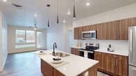 Located at 1111 E Brickyard Rd in Salt Lake City, UT, this well-appointed 2-bedroom, 3-bathroom residence offers a thoughtfully designed single-level layout. The open-concept living area seamlessly connects the dining room, kitchen, and living room, all bathed in natural light and finished with light wood-style flooring. A ceiling fan adds comfort to the living space, which opens to a private balcony with outdoor views.

The kitchen is a standout feature, showcasing rich walnut-toned cabinetry, a white quartz waterfall island with an undermount sink, white subway tile backsplash, and a full suite of stainless steel appliances. Striking cone-shaped pendant lights add a contemporary flair overhead. A pantry provides additional storage convenience.

Both bedrooms are generously sized, carpeted, and filled with natural light from large windows. The spacious primary bedroom includes a well-organized walk-in closet with built-in shelving and hanging rods. Three full bathrooms are finished consistently with wood-look tile flooring, walnut vanities, white quartz countertops, and frameless glass shower enclosures. Additional highlights include three closets, an in-unit laundry room, and a hallway connecting all spaces efficiently throughout the home.