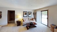This single-floor residence offers a well-organized layout across several distinct living areas. The living room is finished with plush carpeting and features a sliding glass door that introduces natural light and provides outdoor views. Framed artwork adorns the neutral walls, complementing the understated, textured ceiling throughout the unit.

An adjacent area showcases a tiled fireplace with a sleek black surround, accompanied by a raised breakfast bar that connects seamlessly to the kitchen. The kitchen is designed in a galley configuration, featuring tile flooring, ample white cabinetry with wood-toned trim, a double sink, and appliances including a range, refrigerator, microwave, and dishwasher. A closet with bifold doors provides additional storage nearby.

The bedrooms are carpeted and comfortably sized, each equipped with a ceiling fan. One bedroom features a walk-in closet with built-in hanging rods and a window dressed with sheer curtains that allow natural light to filter through. The bathroom includes a full tub and shower combination with white tile surround, a shower curtain rod, and a vanity with storage. Throughout, the space maintains a neutral, cohesive palette suited to a variety of interior styles.