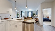 Located at 435 Main St in Hackensack, NJ, this single-floor residence offers a thoughtfully designed open-concept layout that seamlessly connects the kitchen, dining, and living areas. The kitchen is a standout feature, outfitted with crisp white shaker cabinetry, quartz countertops, a subway tile backsplash, and a full suite of stainless steel appliances including a gas range, built-in microwave, dishwasher, and refrigerator. A peninsula with pendant lighting and bar seating provides an ideal space for casual dining or entertaining. The living area is bright and welcoming, with large windows dressed in navy drapes that allow generous natural light to fill the room, complemented by wood-style plank flooring throughout. The bedrooms offer a calm retreat, each featuring plush carpeting, ample natural light from well-sized windows, and comfortable proportions. Two bathrooms serve the residence — one featuring a tub-shower combination with tile surround and a vanity with ample storage, and the other a walk-in shower with a frameless glass door and similar clean finishes. Both bathrooms continue the wood-look flooring found throughout the home, tying the design together cohesively. The overall aesthetic is modern and understated, with a neutral palette and quality finishes throughout.