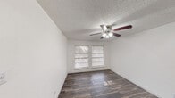 This one-bedroom, one-bathroom unit in Austin, Texas offers a practical and comfortable layout across a single floor. Throughout the space, dark hardwood-style flooring provides a warm, cohesive look that ties each room together. Crisp white walls and textured ceilings create a clean, neutral backdrop, while ceiling fans with integrated lighting fixtures are present in both the living area and bedroom, ensuring year-round comfort. The living room is a well-proportioned space with a window that invites natural light and offers views of the surrounding area. It connects seamlessly to the bedroom, which features its own window for additional natural light and includes a built-in closet with a hanging rod for ample storage. The galley-style kitchen is efficiently designed with rich dark cabinetry, generous countertop space, a stainless steel sink, and an electric range, providing everything needed for everyday cooking. The bathroom is clean and functional, featuring a full soaking tub with a tiled surround and a combined shower. The unit's straightforward layout maximizes the use of available space, making it a practical and well-appointed option in the Austin, TX 78753 area.