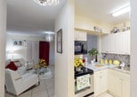 Located at 11020 SW 196th St in Cutler Bay, Florida, this single-story home offers a well-organized layout with tile flooring throughout and a warm, livable character. The kitchen is efficiently designed with white cabinetry, granite-style countertops, a stone tile backsplash, a stainless steel range, and an over-the-range microwave. A pass-through opening connects the kitchen to the adjoining living and dining areas, promoting an open flow. The living room features a decorative chandelier, light-toned walls, and window treatments that allow for privacy while maintaining brightness. The dining area sits adjacent, accented by a modern glass-top table and a striking chandelier overhead. The bedroom is comfortably sized, equipped with a ceiling fan, a window with curtains, and ample storage. The full bathroom includes a granite-topped vanity, a tiled walk-in shower with glass sliding doors, and tile flooring. An additional room, finished with soft green walls and tile floors, offers flexible use as a home office or hobby space. Textured ceilings are consistent throughout the home, and the overall layout, as shown in the dollhouse view, provides a compact yet functional single-floor living experience.