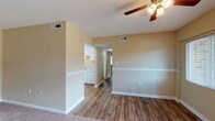 Located at 880 Glendale Dr in Cary, NC, this single-floor home offers a well-organized layout with a warm, neutral color palette of soft beige tones and white trim throughout. The living area features durable hardwood-style flooring, a ceiling fan with light fixture, and an open sightline toward the kitchen, creating a connected and functional flow. A half-wall partition neatly separates the living space from the kitchen corridor, adding architectural interest while maintaining an open feel. The carpeted bedrooms are generously sized, each equipped with ceiling fans and windows that invite natural light and outdoor views of surrounding greenery. One bedroom includes an adjacent walk-in closet, adding practical storage. The kitchen is outfitted with white cabinetry, light granite-style countertops, a built-in electric range, overhead microwave, and a stainless sink — offering a clean and efficient workspace. The bathroom features a full-size soaking tub with a white surround and built-in shelf niche, while a second bathroom includes a vanity with a white sink, wood-style flooring, and a towel bar. Textured ceilings, consistent white baseboards, and HVAC vents are found throughout, contributing to a tidy and cohesive interior aesthetic.