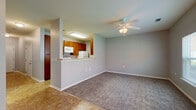 This two-floor residence offers a practical and comfortable layout designed for everyday living. The main level opens into a combined living and dining area finished with plush carpeting and tile flooring, illuminated by a ceiling fan with integrated lighting. The kitchen is accessible via a pass-through counter that overlooks the living space, providing an open and connected feel. Inside, the galley-style kitchen is well-appointed with warm wood cabinetry, light countertops, a full suite of white appliances including an electric range, microwave, refrigerator, and dishwasher, and a stainless steel sink. A glass door on the main level provides direct access to the exterior. A staircase with a white-painted banister and handrail connects the two floors via a hallway with tile flooring. The upper level hosts carpeted bedrooms, each equipped with ceiling fans. At least one bedroom features dual closets, including a walk-in closet with shelving. Two full bathrooms are present, each offering a single-sink vanity with wood cabinetry, a toilet, and a tub-shower combination with tile surround. A dedicated laundry room accommodates a full-size washer and dryer with overhead wire shelving. Neutral gray walls and white trim are consistent throughout, giving the space a clean, cohesive appearance.