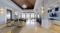 Located at 225 Evernia St in the heart of West Palm Beach, FL, this elegantly designed amenity lounge offers a refined and social atmosphere across a single, expansive floor. The grand entrance greets visitors with soaring floor-to-ceiling glass doors, polished marble tile flooring, and abundant natural light — setting a sophisticated tone from the moment of arrival.

The main living area is thoughtfully appointed with a curated mix of contemporary furnishings, including plush blue and gold seating arrangements anchored by patterned area rugs. A built-in bar with counter seating, a wall-mounted television, and warm pendant and sconce lighting contribute to an inviting, upscale ambiance. An elegant orb chandelier adds a dramatic focal point, complemented by a deep navy ceiling accent that frames the space with bold contrast.

A dedicated game and recreation zone features a billiard table and foosball table, making the space equally suited for leisure and entertainment. Draped linen curtains and tufted banquette seating lend a polished, lounge-like quality to this area.

The adjacent outdoor terrace extends the living experience into the open air, offering generous space for seating and stunning panoramic views of the West Palm Beach skyline and waterway — a standout feature that highlights the property's premier urban location.