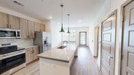 This well-appointed one-bedroom, one-bathroom unit in Birmingham, Alabama offers a thoughtfully designed open-concept layout with modern finishes throughout. The combined kitchen and living area serves as the heart of the home, anchored by a granite-topped kitchen island with an undermount sink and stylish pendant lighting. Natural wood-tone cabinetry lines the kitchen walls, complemented by a classic subway tile backsplash and a full suite of stainless steel appliances, including a refrigerator with ice maker, electric range, and over-the-range microwave. Wood-look flooring flows seamlessly throughout the entire unit, adding warmth and continuity. The living area is bright and open, benefiting from multiple windows and a glass-panel door that invite ample natural light and outdoor views of the surrounding neighborhood. The bedroom is a comfortable, well-lit space with a window and direct access to the full bathroom. The bathroom features granite countertops and connects to a dedicated walk-in closet with wire shelving. Additional storage is provided by multiple closets, including a pantry and a utility closet housing the electrical panel. Five-panel interior doors and recessed lighting add polished, contemporary touches throughout this efficiently laid-out home.