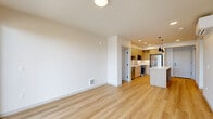Located at 820 N State St in Bellingham, Washington, this thoughtfully designed 2-bedroom, 2-bathroom residence offers a clean, modern aesthetic throughout its single-level layout. The open-concept kitchen and living area serves as the heart of the home, featuring light wood cabinetry, a quartz-topped island with pendant lighting, stainless steel appliances including a gas range, microwave, and refrigerator, a white subway tile backsplash, and matte black fixtures that add a contemporary edge. Light hardwood flooring flows throughout the main living spaces, enhancing the bright and airy feel. The living room opens directly to a private balcony through sliding glass doors, inviting natural light and outdoor views of the surrounding neighborhood. The spacious primary bedroom is carpeted for comfort and includes generous windows that bring in additional natural light. A dedicated walk-in closet with wire shelving provides ample storage. Both bathrooms are finished with warm wood vanities, quartz countertops, and matte black hardware. An in-unit laundry room houses a stacked Whirlpool washer and dryer alongside additional wire shelving for extra storage. A mini-split system in the living area ensures year-round climate comfort. The overall ambiance is fresh, modern, and move-in ready.
