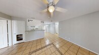 This single-story home offers a practical and well-organized layout encompassing four bedrooms, three bathrooms, and five closets. The open living and dining area features light-toned ceramic tile flooring with a decorative mosaic inlay, a ceiling fan with a light fixture, and direct sightlines to the kitchen — creating a cohesive and airy shared living space. Natural light enters through windows fitted with blinds, and a glass-paneled exterior door further brightens the area.

The kitchen is efficiently designed with white cabinetry, granite-style countertops, a decorative range hood with lattice-detail upper cabinets, a white electric range, and a double sink. A pass-through bar connects the kitchen to the living area, making it ideal for casual dining and entertaining.

The bedrooms are carpeted with tile flooring, neutral gray walls, and windows that allow natural light. Ceiling fans are present in multiple rooms, including one bedroom that also features an electrical panel. The spacious primary bedroom provides a comfortable private retreat.

The bathrooms are finished in white with tile flooring, white vanities, overhead storage cabinets, and mirrors. One bathroom includes a tub-shower combo, while another features a walk-in shower with tiled walls and built-in shelving. The overall aesthetic throughout is clean, neutral, and move-in ready.