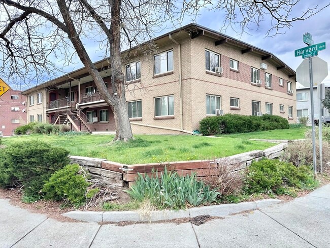 Charming brick apartment building at the corner of a tree-lined street, boasting lush greenery and a classic architectural design. - Parklane Apartments