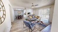 This single-floor residence offers a thoughtfully designed layout encompassing three bedrooms, two bathrooms, a combined living and dining area, and a kitchen — all connected by a central hallway. Wood-look flooring runs consistently throughout the home, lending a cohesive and modern aesthetic.

The open-concept living room is bright and welcoming, featuring a ceiling fan, textured ceiling, and a sliding glass door fitted with vertical blinds that allows natural light to pour in and provides access to the outdoors. The space flows seamlessly into the dining area, which is distinguished by a raised tray ceiling detail and is positioned adjacent to the kitchen. The kitchen is equipped with white cabinetry, tile backsplash, and includes a stainless steel refrigerator and black appliances, with a vertical window providing additional natural light.

The primary bedroom offers a built-in closet with shelving and hanging space, and connects directly to a private en-suite bathroom featuring vanity cabinetry and a mirror with overhead lighting. Two additional bedrooms are well-sized and bright, each with windows that invite natural light. Both bathrooms are finished with wood-look tile flooring and shower-tub combinations. The hallway efficiently connects the private and shared areas of the home, completing a functional and comfortable floor plan.