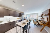 Located at 21 Charles St in Cambridge, MA, this thoughtfully designed one-bedroom, one-bathroom residence offers a smart, efficient layout with modern finishes throughout. The open-concept living and kitchen area is anchored by large windows that flood the space with natural light and frame views of the surrounding Cambridge streetscape. Light-toned hardwood-style flooring runs continuously through the main living areas, creating a cohesive and airy feel.

The kitchen is outfitted with rich dark-wood cabinetry extending to the ceiling, white quartz countertops, a classic subway tile backsplash, and a full suite of stainless steel appliances including a gas range, built-in microwave, dishwasher, and a large French door refrigerator. A breakfast bar island provides additional seating and prep space.

The living room benefits from an oversized triple window that bathes the area in daylight and offers pleasant street views. The bedroom features dual windows, light wood flooring, and ample closet space. The unit also includes three closets total and an in-unit laundry area for added convenience.

The bathroom is finished with floor-to-ceiling white subway tile, grey floor tile, a soaking tub with shower, matte black fixtures, and a modern vanity, delivering a clean, contemporary aesthetic throughout.