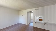 Located at 1150 West University Drive in Tempe, Arizona, this one-bedroom, one-bathroom unit offers an efficiently arranged single-floor layout. The living room features wall-to-wall carpet and a textured ceiling, with an open sightline to the kitchen via a pass-through countertop — a practical design detail that helps the compact space feel more connected and functional. The kitchen is equipped with warm wood-toned cabinetry and a white range, providing essential cooking amenities in a clean, organized layout. The bedroom is a cozy, carpeted room with a window fitted with vertical blinds that allow for natural light and privacy. It includes a dedicated closet with built-in shelving, offering useful storage. An additional smaller room, also carpeted with panel-style walls, provides flexible space that could serve as a home office or storage area. The bathroom features wood-look flooring, a granite-style countertop with an undermount sink, wood-toned cabinetry, and a full bathtub and shower combination. Neutral white walls throughout create a clean, bright ambiance. This unit is ideally situated near Arizona State University, making it well-suited for students or professionals seeking a practical, low-maintenance space in a central Tempe location.