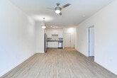 This single-story residence in LaGrange, Georgia, presents a clean, modern interior designed for comfortable everyday living. The open-concept layout connects the kitchen directly to the living area, creating a seamless flow that maximizes the sense of space. Wood-style plank flooring runs throughout the main living areas, lending a warm, cohesive aesthetic, while a ceiling fan and pendant lighting provide functional illumination.

The kitchen is well-appointed with white shaker-style cabinetry, granite countertops, and a full suite of stainless steel appliances, including a refrigerator, range, microwave, and dishwasher. A track lighting fixture overhead and a stainless undermount sink complete the space. Natural light enters the living area through a window fitted with blinds.

The bedrooms are carpeted for comfort and feature neutral wall tones, ample wall space, and windows that bring in natural light. The bathroom continues the granite countertop theme with white cabinetry, a large vanity mirror, and a standalone walk-in shower with wood-style flooring. Overall, the unit offers a consistent, contemporary finish throughout all spaces.