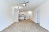 This single-story residence in LaGrange, Georgia, presents a clean, modern interior designed for comfortable everyday living. The open-concept layout connects the kitchen directly to the living area, creating a seamless flow that maximizes the sense of space. Wood-style plank flooring runs throughout the main living areas, lending a warm, cohesive aesthetic, while a ceiling fan and pendant lighting provide functional illumination.

The kitchen is well-appointed with white shaker-style cabinetry, granite countertops, and a full suite of stainless steel appliances, including a refrigerator, range, microwave, and dishwasher. A track lighting fixture overhead and a stainless undermount sink complete the space. Natural light enters the living area through a window fitted with blinds.

The bedrooms are carpeted for comfort and feature neutral wall tones, ample wall space, and windows that bring in natural light. The bathroom continues the granite countertop theme with white cabinetry, a large vanity mirror, and a standalone walk-in shower with wood-style flooring. Overall, the unit offers a consistent, contemporary finish throughout all spaces.
