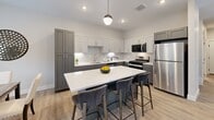 Located at 6420 Harvey St in Muskegon, Michigan, this well-appointed two-story home offers 3 bedrooms and 3 bathrooms across two thoughtfully designed floors. The main level features an open-concept living, dining, and kitchen area filled with natural light from multiple windows. The living room is anchored by a sleek fireplace and durable light-toned luxury vinyl plank flooring that flows seamlessly throughout the space. A sliding glass door provides outdoor views and additional light. The kitchen is outfitted with two-tone shaker cabinetry — gray lower cabinets paired with white uppers — white quartz countertops, a subway tile backsplash, under-cabinet lighting, and stainless steel appliances including a dishwasher. A pendant-lit breakfast bar connects the kitchen to the dining area, which enjoys garden views through large windows. A convenient half bath is also found on this floor. Upstairs, the spacious primary bedroom includes generous closet space, while the additional bedrooms feature plush carpeting, ample natural light, and double closets. The full bathrooms are finished with gray vanities, white countertops, and vinyl plank flooring. With six closets total and two staircases, this home delivers both practical storage and an efficient, comfortable layout.