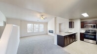 Located on E 121st St S in Broken Arrow, Oklahoma, this two-story home offers 2 bedrooms, 3 bathrooms, and a well-designed layout across two floors. The main living level hosts a bright, open-concept kitchen and living room combination filled with natural light from a bank of windows. The living area features plush carpeting and a sleek, modern linear fireplace built into the wall, adding a striking focal point to the space. A ceiling fan overhead enhances comfort throughout.

The kitchen is outfitted with rich dark cabinetry, stainless steel appliances including a refrigerator, range, and microwave, and a marble-look countertop peninsula with an integrated sink. Light tile flooring in the kitchen contrasts cleanly with the carpeted living area.

The generously sized primary bedroom includes soaring ceilings, a ceiling fan, and direct access to a private en-suite bathroom and a spacious walk-in closet with extensive wire shelving and hanging systems. An additional bedroom and bathrooms complete the upper floor.

The home also includes an attached garage with an automatic opener, as well as a utility closet housing the electrical panel. Neutral tones and clean finishes throughout lend the space a move-in-ready feel.
