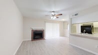 This thoughtfully designed single-floor residence offers a comfortable and efficient layout across one bedroom and one bathroom. The combined living and dining area serves as the heart of the home, highlighted by a classic brick fireplace with a white-painted mantle and a ceiling fan with integrated lighting. Light wood-tone laminate flooring flows throughout the entire space, complementing the neutral, warm-toned walls and creating a cohesive aesthetic. Vertical blinds covering a large sliding glass door allow for adjustable natural light in the living area.

The galley-style kitchen is efficiently arranged with white cabinetry, granite-look countertops, a marble-style tile backsplash, and black appliances including an electric range and dishwasher. A pass-through window connects the kitchen to the living area, enhancing the open feel.

The bedroom is a generously proportioned retreat with its own ceiling fan, a window with natural light, and direct access to a walk-in closet equipped with built-in shelving and hanging rods. The full bathroom features a tub-shower combination, a granite-top vanity with white cabinetry, and a large mirror. A hallway connects the main living spaces, completing the functional floor plan.