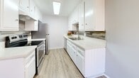 Located at 23930 Ocean Ave in Torrance, CA, this single-floor unit offers a clean, modern aesthetic throughout its well-maintained interior. The living area is bright and open, featuring warm laminate wood flooring and a large sliding glass door dressed with vertical blinds that allows abundant natural light to fill the space. A ceiling fan with integrated lighting adds both function and comfort to the living area.

The kitchen is a standout feature, designed in a galley layout with crisp white shaker cabinetry, light stone-finish countertops, a tile backsplash with subtle patterning, and stainless steel appliances including a refrigerator and range. A skylight panel above keeps the kitchen bright and inviting.

The bedrooms continue the laminate flooring theme and are dressed in a neutral gray palette with white trim. One bedroom includes a mirrored sliding closet, while multiple rooms feature large windows with vertical blinds providing ample light and privacy. The bathroom is accessible from the hallway and offers white cabinetry, a single vanity with a mirror, and updated lighting fixtures.

Throughout the unit, textured ceilings, consistent flooring, and a cohesive cool-gray color scheme create a tidy, move-in-ready environment suited for comfortable everyday living.