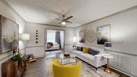 This thoughtfully designed 2-bedroom, 2-bathroom residence spans a single floor and delivers a comfortable, functional layout with stylish finishes throughout. The open-concept living, dining, and kitchen area forms the heart of the home, featuring durable wood-look flooring, crown molding, and a textured ceiling with a ceiling fan overhead. The living room offers generous space for seating and receives natural light through large windows dressed with blinds and curtains. Adjacent to the living area, the dining space accommodates a full dining set beneath a chandelier and flows seamlessly into the kitchen. The kitchen is equipped with stainless steel appliances, white cabinetry, dark countertops, and a skylight that brightens the space. The spacious primary bedroom features plush carpeting, a ceiling fan, and a sliding glass door with vertical blinds that invites natural light. It is complemented by a large walk-in closet with wire shelving. The second bedroom is equally comfortable with ample natural light. Two bathrooms serve the residence, one of which includes an in-unit washer and dryer tucked behind louvered closet doors. Both bathrooms feature white vanities with dark countertops and shower-tub combinations, providing practical everyday functionality throughout.