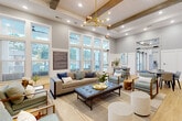 Located at 2465 Richardson Pkwy in Jonesboro, GA, this clubroom is a thoughtfully designed community gathering space that blends modern farmhouse aesthetics with contemporary comfort. The single-floor layout is anchored by soaring ceilings adorned with exposed wood beams and white shiplap detailing, creating an airy, upscale atmosphere throughout.

The main lounge area is generously proportioned, featuring a curated seating arrangement of neutral sofas, tufted ottomans, and gold-framed accent chairs centered around a mounted flat-screen television. A bold, chevron-patterned deep blue accent wall serves as a dramatic focal point, repeated in two distinct areas of the space and complemented by coordinating artwork and décor.

A well-equipped refreshment area includes gray shaker cabinetry, a crisp white quartz countertop, a full-size stainless steel refrigerator, and a decorative teal mosaic tile backsplash. A coffee and beverage station adds convenience for everyday use.

The dining area accommodates multiple seating configurations with both round and long communal tables, ideal for casual gatherings or events. Light hardwood flooring flows seamlessly throughout, while large windows and multiple sets of French doors flood the interior with natural light and provide views of the outdoor pool area. A mid-century modern sputnik chandelier and oversized pendant lights complete the refined, welcoming ambiance.