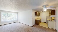 Located at 1325 Atlas St in Rapid City, South Dakota, this 2-bedroom, 1-bathroom unit offers a functional single-floor layout. The combined kitchen and living room forms the heart of the home, where the living area features wall-to-wall carpeting, a ceiling fan, a large window with vertical blinds, and a baseboard heating system. The kitchen transitions seamlessly from the living space and is equipped with dark wood cabinetry on both sides, a double-basin sink with light-toned countertops, a white electric range, a refrigerator, and tile flooring.

Both bedrooms are carpeted and bright, each benefiting from natural light through windows overlooking greenery. The primary bedroom offers a spacious feel and features a sliding-door closet with built-in shelving, while the second bedroom also includes closet storage. Textured popcorn ceilings are consistent throughout the unit.

The bathroom is clean and efficiently designed, featuring a shower-tub combination, a wall-mounted pedestal sink, a toilet, tile flooring, and a wood-framed medicine cabinet with overhead lighting. A hallway connects the private and shared areas of the unit, completing the practical and straightforward floor plan.