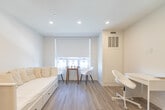 Located at 695 Niagara St in Welland, Ontario, this thoughtfully designed studio unit makes efficient use of its single-floor layout, offering a complete and functional living environment. Light hardwood-style flooring runs throughout the space, complemented by crisp white walls and recessed ceiling lighting that create a bright, clean atmosphere.

The galley-style kitchen is well-appointed with white shaker cabinetry, stainless steel appliances including a full-size refrigerator, electric range, and built-in microwave, along with a double basin sink and ample counter space. The kitchen flows seamlessly into the main living area, which accommodates a sofa-style daybed and a compact side table, maximizing usability without sacrificing comfort.

At the far end of the unit, natural light filters in through a window fitted with a roller shade, illuminating a cozy dining nook with a small round table and two modern chairs. A dedicated workspace with a white desk and chair is neatly tucked beside the window area, ideal for studying or remote work. A smart home panel is also visible on the wall, indicating modern building integration.

The bathroom features a white vanity with under-sink storage, a well-lit mirror, a toilet, and a bathtub, all finished in a clean, contemporary style consistent with the rest of the unit. In-unit laundry is also included, as visible in the dollhouse view.