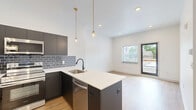 Located on Germantown Avenue in Philadelphia's Germantown neighborhood, this thoughtfully designed one-bedroom, one-bathroom unit offers a modern aesthetic with high-quality finishes across a single floor. The open-concept living and kitchen area serves as the heart of the space, showcasing warm hardwood-style flooring, recessed lighting, and large windows that invite abundant natural light. The kitchen is a standout feature, equipped with dark cabinetry, a sleek grey subway tile backsplash, stainless steel appliances including a refrigerator, range, microwave, and dishwasher, and a peninsula with a white quartz countertop and pendant lighting overhead. The kitchen flows seamlessly into the living area, creating an ideal layout for everyday living. A private balcony off the main living space offers open views of Germantown Avenue and the surrounding neighborhood's tree-lined streetscape. The bedroom provides a comfortable and quiet retreat with hardwood-style flooring and a well-positioned window with natural light. Two closets offer ample storage throughout the unit. The bathroom features large-format tile flooring, a tub-shower combination with tall dark vertical tile surround, a warm wood vanity, and matte black fixtures. In-unit laundry adds everyday convenience to this well-appointed space.