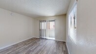 Located at 990 E River Rd in Tucson, Arizona, this single-floor unit offers a clean, functional layout with consistent wood-look flooring throughout, lending warmth and visual continuity across every room. The living area is bright and open, featuring a sliding glass door fitted with vertical blinds that allows natural light to pour in while providing access to an outdoor area. An additional window further enhances the sense of openness in this space. A second room, well-suited as a bedroom, mirrors this brightness with its own window and the same durable wood-look flooring underfoot. Both rooms feature textured ceilings that add subtle character to the neutral, light-colored walls. The kitchen is practical and well-equipped, featuring ample cabinetry with warm wood trim, dark granite-look countertops, and a full suite of black appliances including a range, over-the-range microwave, and refrigerator. A built-in sink with a window nearby adds functionality to the cooking space. The bathroom is clean and straightforward, offering a tiled tub-and-shower combination, a toilet, and coordinating wood-look flooring that ties the space together. Overall, the unit presents a neat, move-in-ready environment in a convenient Tucson location.
