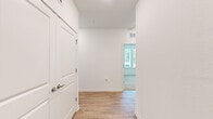 This well-appointed single-floor residence offers a thoughtfully designed layout with modern finishes throughout. The interior is anchored by a bright, open-concept kitchen that serves as the heart of the home. Outfitted with grey shaker-style cabinetry, a crisp white subway tile backsplash, quartz countertops, and a full suite of stainless steel appliances — including a refrigerator, range, microwave, and dishwasher — the kitchen also features a large central island with pendant lighting overhead, ideal for both meal prep and casual dining. Light hardwood-style flooring flows throughout the main living and hallway areas, lending warmth and continuity to the space. The hallway connects the rooms with ease, featuring a paneled entry door and clean white walls. The bedrooms are finished with plush neutral carpet and ceiling fans, while large windows fitted with white blinds invite generous natural light and views of the surrounding neighborhood. At least one bedroom includes a sliding closet and access to an additional walk-in storage area. The bathroom is finished with matching grey cabinetry, a white quartz countertop, an undermount sink, a large framed mirror, and a tiled shower stall. The overall aesthetic is clean, contemporary, and move-in ready.