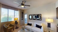 This single-floor residence offers a thoughtfully designed layout with a consistent neutral color palette and warm finishes that create a cohesive, inviting atmosphere throughout. The kitchen is well-equipped with dark espresso cabinetry, granite countertops, stainless steel appliances including a refrigerator, range, and microwave, and rich hardwood-style flooring. Track lighting overhead adds a modern touch. A granite-topped island provides additional prep space and transitions seamlessly toward the dining area, which features a dark dining set with green upholstered chairs.

The living room is carpeted and features a ceiling fan with light fixture, built-in shelving, and a patio door that allows natural light to filter in. A decorative triple-circle mirror serves as a focal point above the sofa area, complementing the neutral tones of the space.

Both bedrooms are carpeted and include ceiling fans, generous natural light, and sliding glass doors leading to a private outdoor patio. The bedrooms feature accent walls and framed wall art, contributing to a polished aesthetic. The bathroom includes a tub-shower combination with sliding glass doors, a dark wood vanity with a white countertop, and wood-look tile flooring, balancing function with style.