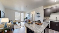 This well-appointed one-bedroom, one-bathroom residence in Broomfield, Colorado offers a thoughtfully designed open-concept layout that seamlessly connects the kitchen and living areas. The kitchen is a standout feature, showcasing rich dark cabinetry, granite countertops, a breakfast bar island with seating, and a full suite of stainless steel appliances including a dishwasher, range, microwave, and refrigerator. Light wood-style flooring flows throughout the main living areas, enhancing the bright, airy feel.

The living room is generously proportioned, filled with natural light from large windows and a glass exterior door that opens to the outdoors. The bedroom offers a comfortable retreat with plush carpeting, a ceiling fan, and a window providing additional natural light, alongside direct access to a spacious walk-in closet with multi-tier wire shelving systems.

The bathroom continues the upscale aesthetic with granite countertops, dark cabinetry, and a large mirror. A dedicated in-unit stacked washer and dryer is conveniently located within the bathroom area. A hallway connects all rooms, completing this efficient and stylish single-floor layout ideal for modern living in Broomfield, CO.