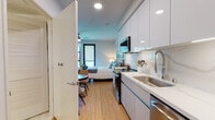 Located at 1641 Lincoln Blvd in Santa Monica, CA, this thoughtfully designed studio offers a streamlined, open-concept layout that efficiently combines living, sleeping, and dining areas on a single floor. Light wood flooring flows throughout, lending warmth and continuity to the space.

The kitchen is a standout feature, outfitted with floor-to-ceiling white flat-panel cabinetry, a marble-style backsplash, white quartz countertops, and a full suite of stainless steel appliances including a refrigerator, range, over-the-range microwave, and dishwasher. A deep stainless steel sink with a flexible coil faucet completes the functional and modern cooking space.

The main living area accommodates a full sleeping zone alongside a seating area, with black-framed windows that invite natural light and offer views of the surrounding neighborhood. A ceiling fan provides year-round comfort. Recessed lighting throughout ensures a bright and clean ambiance.

The bathroom is finished with hexagonal marble-look tile flooring, a sleek floating vanity with a white countertop, an LED-backlit mirror, and a tub-shower combination. The overall design palette — crisp whites, neutral tones, and natural wood accents — creates a cohesive, contemporary aesthetic well-suited to the Santa Monica lifestyle.