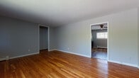 Located at 1271 Burnside Ave in East Hartford, Connecticut, this single-floor unit offers a clean, well-maintained living environment with a cohesive design throughout. The living areas are finished with warm-toned hardwood flooring that runs seamlessly through multiple rooms, complemented by neutral gray walls and crisp white trim that create a bright, inviting atmosphere. Large windows dressed with vertical blinds allow generous natural light to fill the space, while baseboard heating provides practical climate control throughout. Ceiling fans in key areas add to the overall comfort of the unit. The kitchen is a standout feature, outfitted with an abundance of white shaker-style cabinetry extending to the ceiling, stone-look countertops, a subway tile backsplash, a stainless steel sink, and stainless steel appliances including a gas range and refrigerator. Wood-look vinyl flooring grounds the kitchen area. The bedroom spaces are generously proportioned, each featuring hardwood floors and ample natural light, with one room including a dedicated closet and a wall-unit air conditioner. The bathroom is tastefully updated with floor-to-ceiling white rectangular tile, an accent stripe of navy mosaic tile, a soaking tub, and a white vanity, all accented by wood-look tile flooring.