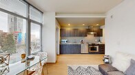 Located at 206 Bell St, Unit 507 in Seattle's Belltown neighborhood, this one-bedroom, one-bathroom residence offers a well-designed urban living experience. The open-concept layout seamlessly connects the kitchen, dining, and living areas, creating a functional and cohesive space. Light hardwood flooring flows throughout the main living areas, adding warmth and continuity.

The kitchen is outfitted with sleek dark wood cabinetry, granite-style countertops, stainless steel appliances including a range, dishwasher, and microwave, and a wall-mounted range hood — combining both style and practicality. The living and dining area benefits from large floor-to-ceiling windows that frame impressive city skyline views and fill the space with natural light.

The bedroom features plush carpeting, generous windows with city views, and access via a sliding glass door, providing a quiet retreat. A dedicated closet adds storage convenience. The combined bathroom and laundry room includes tile flooring, a granite-topped vanity, grab bar, and in-unit washer, all served by a window for natural ventilation. A private balcony extends the living space outdoors, perfect for taking in Seattle's urban scenery.