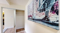 Located at 14215 Grand Pre Rd in Silver Spring, Maryland, this single-floor unit offers a practical and comfortable layout designed to maximize livability. The open living area is finished with plush carpeting and features sliding glass doors that lead to a private balcony, filling the space with natural light and providing a connection to the outdoors. Adjacent to the living area, a dining space is defined by a pendant light fixture and additional windows that bring in further natural illumination, with light wood-style flooring continuing the clean aesthetic.

The kitchen is well-appointed with light wood cabinetry offering ample storage, stone-toned countertops, and a full suite of black appliances including a range, over-the-range microwave, and refrigerator. Light wood-style flooring carries through this area, contributing to a cohesive, easy-to-maintain finish.

The bedrooms are carpeted and feature neutral, warm-toned walls. Each room includes dedicated closet space—one with a sliding mirrored door and built-in rod, another with a walk-in style closet. Windows in the bedrooms allow natural light to filter in, creating a bright and restful environment.

The bathroom includes a full tub-shower combination with white tile surround, chrome fixtures, and wood-style flooring, maintaining the consistent, clean design found throughout the unit.