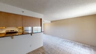 Located at 8145 E Camelback Rd in Scottsdale, Arizona, this single-floor unit offers an efficient and functional layout across a compact footprint. The open-concept kitchen and living area form the heart of the space, making smart use of every square foot. The living room features neutral-toned carpet, warm beige walls, and a textured ceiling, with a large window dressed in vertical blinds that allows natural light to filter in and offers a view of the outdoor surroundings. The kitchen is thoughtfully appointed with light wood cabinetry, dark granite-style countertops, a double-basin sink, and wood-look flooring that adds warmth to the space. A peninsula counter connects the kitchen to the living area, creating a natural transition between the two zones. Appliances, including a refrigerator and dishwasher, are integrated into the kitchen layout. A solid wood entry door provides a defined entryway leading directly into the combined living and kitchen space. The bathroom is clean and simply designed, featuring a full tub and shower combo with chrome fixtures, wood-look flooring, and bright white walls that contribute to a fresh, functional atmosphere. This unit offers a straightforward, no-frills living environment well-suited to those seeking practical accommodations in the heart of Scottsdale.
