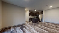 This thoughtfully designed single-floor residence combines contemporary finishes with a functional open layout. The kitchen serves as the centerpiece of the living space, showcasing rich dark espresso cabinetry, granite countertops, a central island, and a full suite of stainless steel appliances including a gas range, microwave, dishwasher, and refrigerator. Wood-look plank flooring flows throughout the main living and kitchen areas, adding warmth and visual continuity.

The living area is generously proportioned and opens to an outdoor patio or balcony through a glass sliding door, allowing natural light to fill the space. The bedrooms are carpeted for comfort and feature neutral tones with large windows that frame views of the surrounding neighborhood.

Two full bathrooms are finished with large-format stone-look tile flooring and matching tiled shower surrounds. One bathroom includes a soaking tub with a tiled surround, while the other features a glass-enclosed walk-in shower. Both bathrooms are equipped with dark vanity cabinetry and white countertops, maintaining a consistent, polished aesthetic throughout the residence. The overall design is clean, modern, and move-in ready.