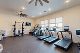 Located at 6426 Dellridge Place in Chattanooga, Tennessee, this fitness center offers a comprehensive and thoughtfully designed exercise space. The room is finished with durable rubber flooring throughout most of the area, with a dedicated green turf section ideal for functional training and floor exercises.

The cardio zone features multiple treadmills and an elliptical trainer, all positioned along a wall of large windows that provide ample natural light and views of the surrounding outdoor landscape — an inviting backdrop for any workout. A stair climber and stationary bike round out the cardio offerings.

On the strength training side, the space includes a multi-functional cable machine, a squat rack with bench press, a leg press machine, a wall-mounted stall bar for stretching and bodyweight exercises, and a freestanding equipment rack stocked with medicine balls, resistance bands, and accessories. A wall-mounted flat-screen TV is positioned for easy viewing from multiple areas of the room.

Multiple large ceiling fans keep air circulating throughout the space. A built-in dual water fountain is conveniently located near the entrance, alongside a restroom. A glass-panel door provides direct access to the outdoors. The walls are finished in a clean white with a bold deep teal accent, adding a polished and energizing aesthetic to the overall environment.