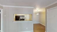This single-story 1-bedroom, 1-bathroom unit offers a practical and comfortable layout with thoughtful design details throughout. Rich, dark hardwood-style flooring flows seamlessly across the main living areas, creating a warm and cohesive aesthetic.

The living room is bright and open, featuring crown molding, neutral-toned walls, and a sliding glass door fitted with vertical blinds that allows natural light to pour in while providing access to an outdoor area with views of surrounding greenery.

The kitchen is efficiently designed with white cabinetry, a subway tile backsplash, granite-style countertops, and black appliances including a refrigerator and electric range. A pass-through window with a breakfast bar counter connects the kitchen to the living and dining area, enhancing the open feel of the space. A pendant light fixture adds a refined touch to the dining area.

The bedroom is a comfortable retreat, complete with crown molding, a ceiling fan, and a window with blinds that frames natural outdoor views.

The bathroom features a dark-stained vanity with a white countertop, a lighted mirror, and a full tub/shower combination, all finished with clean, neutral tones.

Throughout the unit, consistent hardwood-style flooring and white baseboards tie the space together for a polished, move-in-ready appearance.