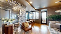 Located at 2025 Cleveland Ave in Charlotte's vibrant South End neighborhood, this sophisticated rooftop lounge offers a seamlessly blended indoor-outdoor experience across a well-appointed single floor. The space is divided into two distinct living areas, each thoughtfully designed to balance comfort and style.

The interior living area exudes warmth and character, highlighted by bold botanical wallpaper, rich wood-toned millwork, and warm hardwood flooring. Pendant globe light fixtures hang from a tray ceiling finished in a deep navy tone, casting an inviting glow over a curated mix of leather seating, upholstered lounge chairs, and banquette-style café nooks with marble-top tables — all framed by large black-trimmed windows overlooking the Charlotte skyline.

Transitioning outdoors, the expansive rooftop terrace is anchored by dramatic dark steel pergola beams and large-format tile flooring. This area offers multiple seating configurations, including plush modular sofas, round wicker daybeds, and accent chairs surrounding a fireplace with decorative tilework and a mounted television. An outdoor kitchen area with bar seating adds functional versatility. Panoramic views of the Charlotte cityscape serve as a stunning backdrop throughout, making this rooftop a premier setting for both relaxation and social gatherings.